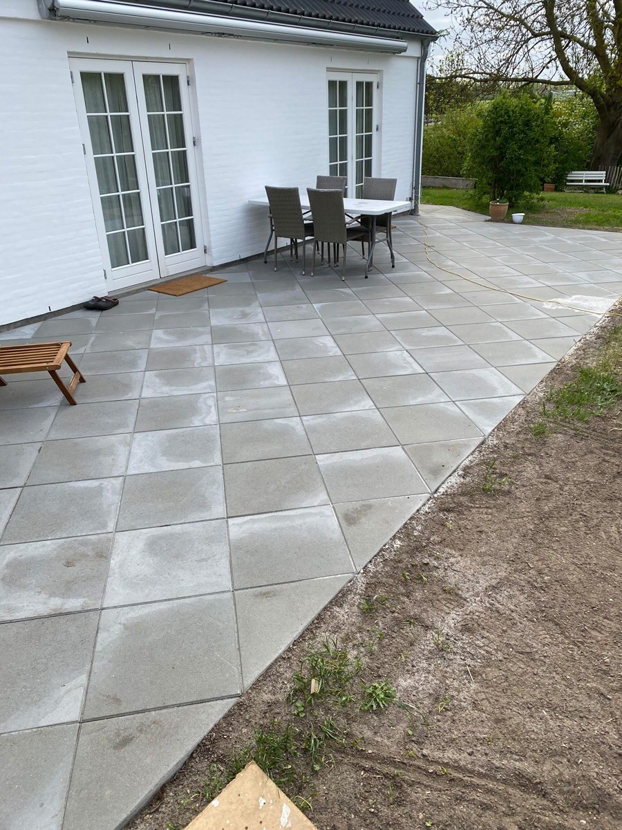 Stor terrasse med betonbelægning langs bondehus i Hørsholm af Haarkjær Byg
